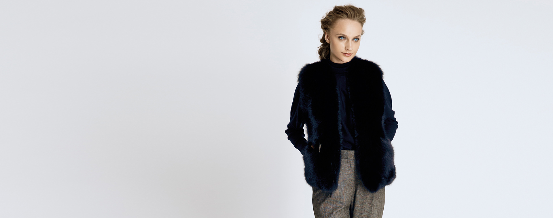 Egy elegáns nő fekete női szőrmemellényt visel egy monokróm öltözék felett. Egy elegáns nő fekete női szőrmemellényt visel egy monokróm öltözék felett.