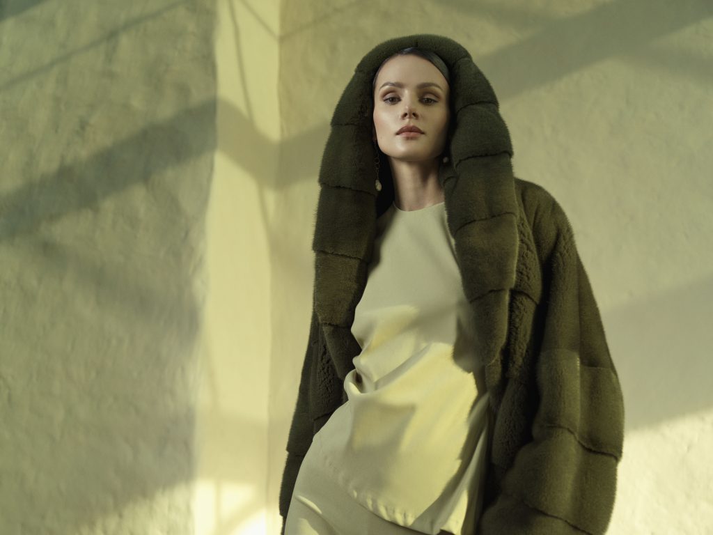 Close up of a hand feeling the dense underfur of a high quality brown mink coat.