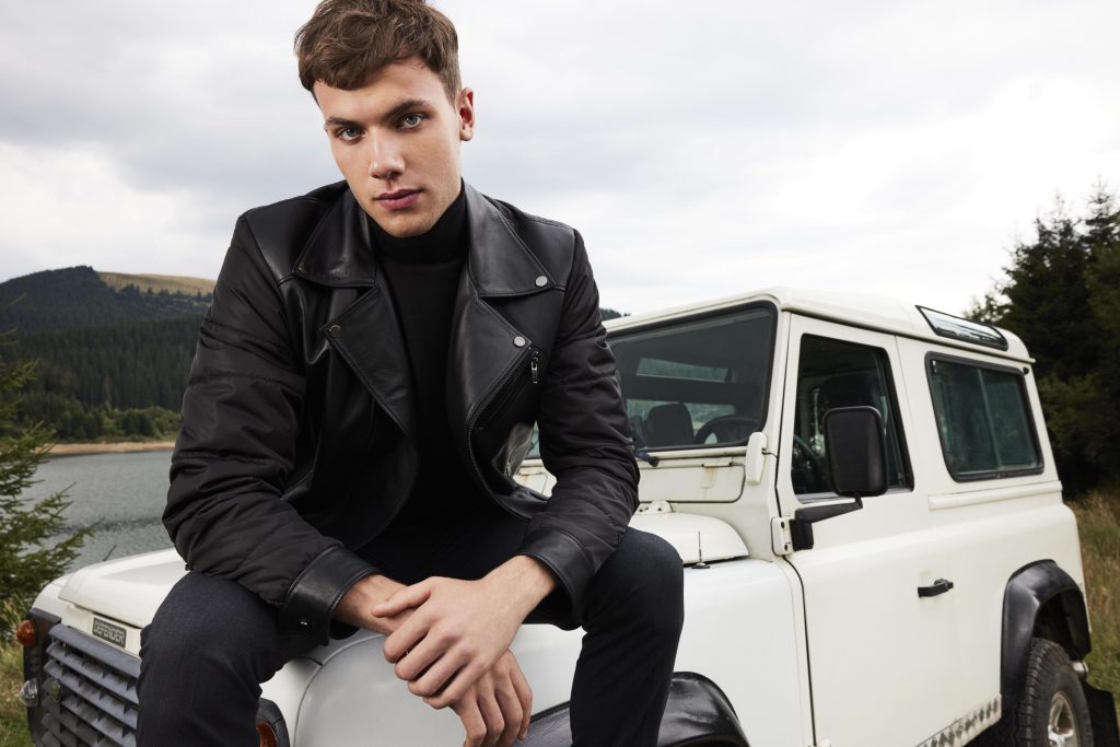 A man wear a black biker jacket on a Defender